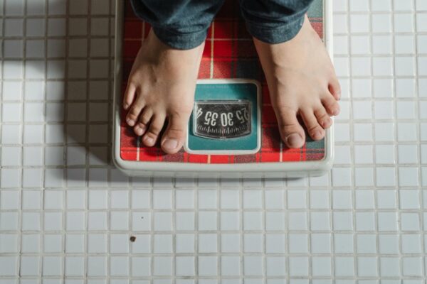 osoba stoi na wadzę i liczy zrzucone kilogramy na diecie